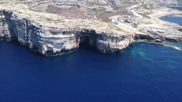 Aerial view of the rugged limestone cliffs and deep blue Mediterranean sea at Dwejra Bay on the coast of Gozo region, Malta. High quality 4k footage