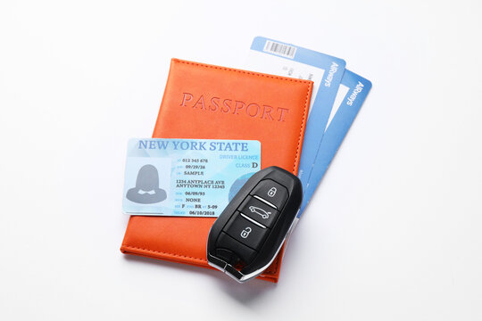 Driver's licence, passport with tickets and car key on white background