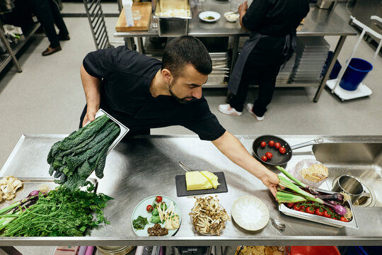 High angle view of male chef organizing fresh vegetables on kitchen counter
