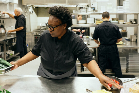 Female chef organizing food items at restaurant kitchen counter