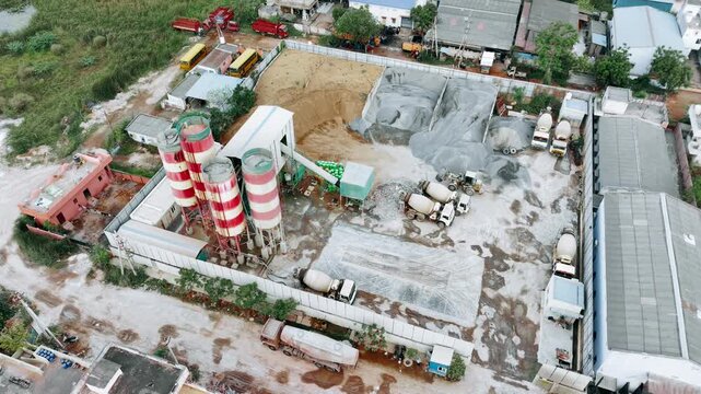 Aerial video of construction equipment dropping and segregating cement and sand at a materials yard