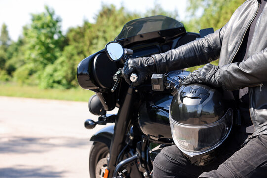 Man with helmet on modern motorcycle outdoors, closeup. Space for text