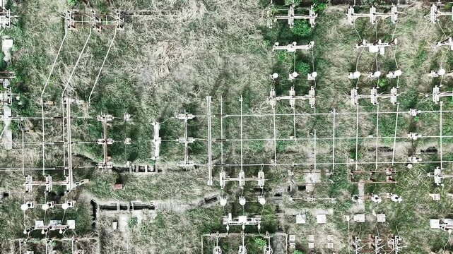 Drone footage flying over a high voltage electrical substation with rows of transformers and busbars