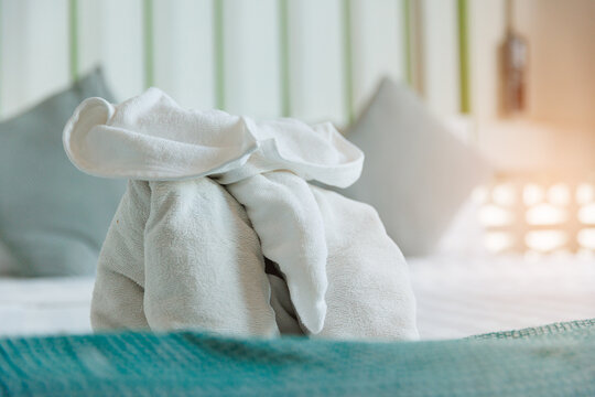 Closeup towel elephant on hotel bed with teal runner and warm soft light for room background and welcome presentation