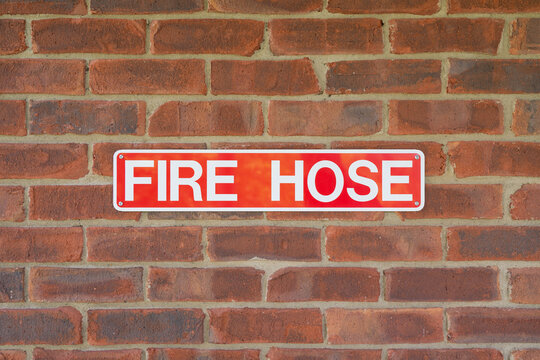 Red and white Fire Hose sign on brick wall background.