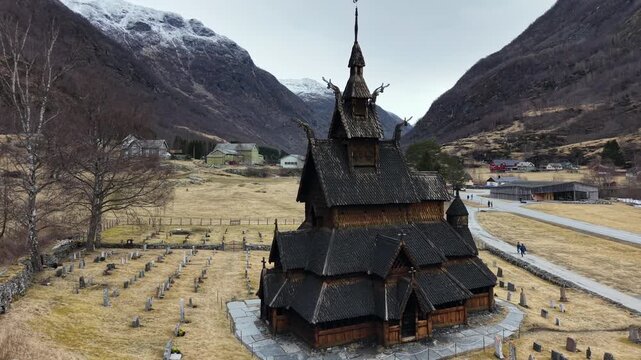 Drone shot of historic wooden stave church in Borgund surrounded by green hills, spring