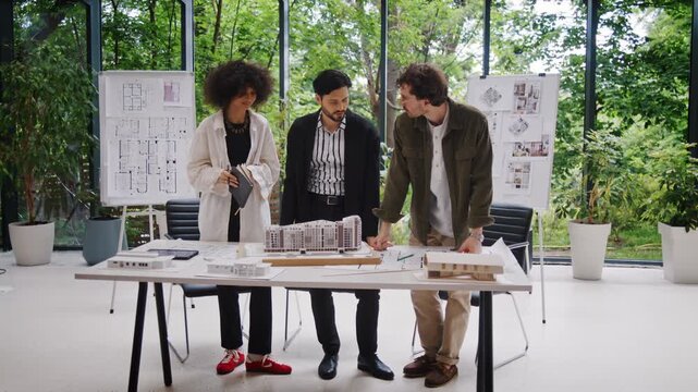 Multiracial team exchanges ideas about apartment buildings model