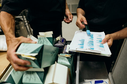 Midsection of professional kitchen workers checking delivery orders