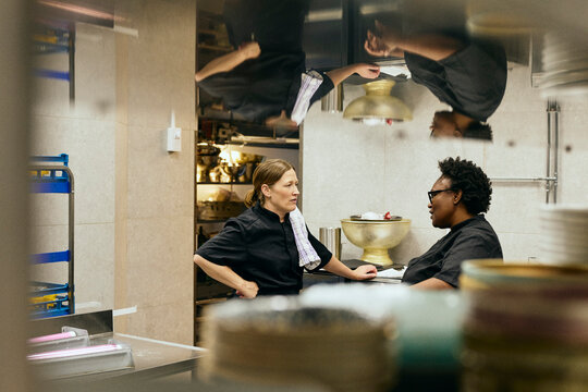 Two female chefs chatting during their shift in restaurant kitchen