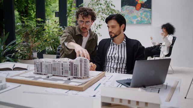 Male architects present ideas for design of multi-story building