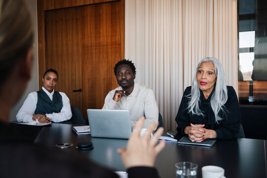 Group of serious corporate workers having discussion in meeting room