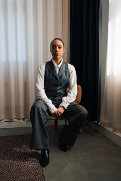 Full length of businesswoman sitting confidently on chair at office