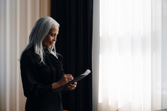 Senior businesswoman reviewing documents near window at office