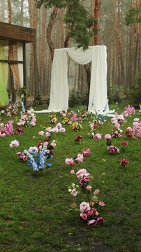 Vertical video. Rain falling over wedding arch draped with white fabric during outdoor ceremony.