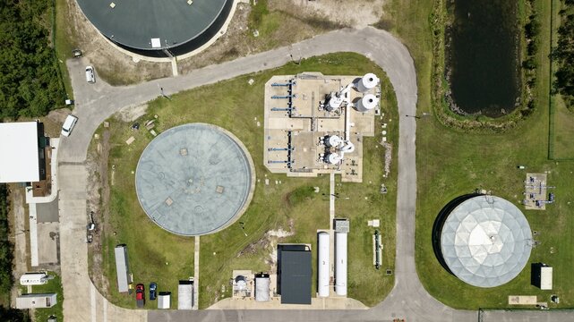 Aerial view of a water treatment facility with circular storage tanks, industrial processing units, and paved access roads in World Golf Village, Florida, United States.
