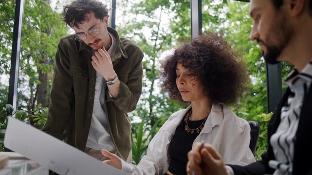 Black woman designer explains blueprint details to colleagues
