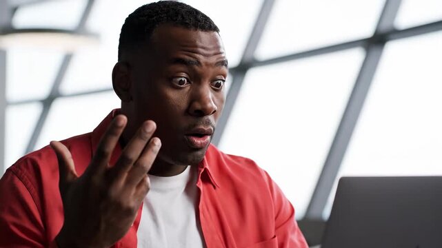 Shocked African American man reacting to unexpected news on his laptop with a surprised expression.