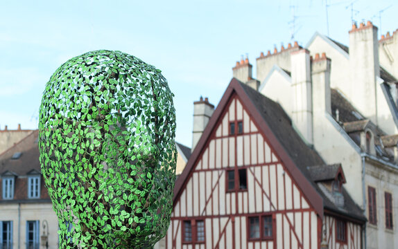 DIJON, FRANCE &ndash; APRIL 29, 2026: Sculpture of a fake head made of metal leafs called Sempervirens, created by the artist Gloria Friedmann in 2013, with half-timbered house in the back. Selective focus