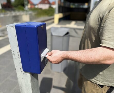 Passenger validating a public transport ticket using a contactless transit card at an electronic ticket validator before boarding a commuter train. Urban mobility and cashless travel concept.