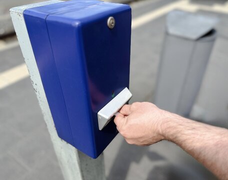 Passenger validating a public transport ticket using a contactless transit card at an electronic ticket validator before boarding a commuter train. Urban mobility and cashless travel concept.