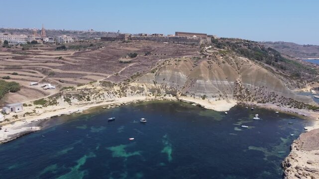 Steep Clay Cliffs in Gozo Malta During Sunny Weather Featuring Earthy Tones and Deep Blue Sea, aerial view near Xatt L-Ahmar salt pans. High quality 4k footage