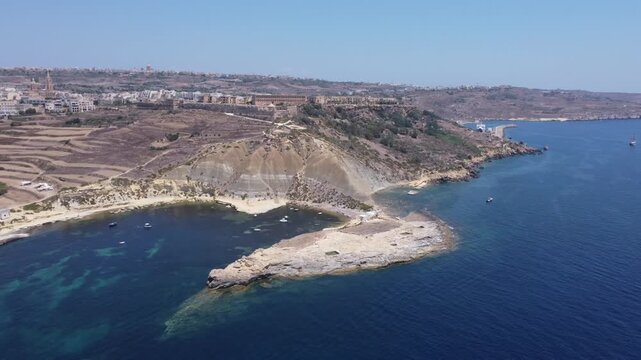 Steep Clay Cliffs in Gozo Malta During Sunny Weather Featuring Earthy Tones and Deep Blue Sea, aerial view near Xatt L-Ahmar salt pans. High quality 4k footage