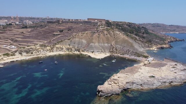 Steep Clay Cliffs in Gozo Malta During Sunny Weather Featuring Earthy Tones and Deep Blue Sea, aerial view near Xatt L-Ahmar salt pans. High quality 4k footage