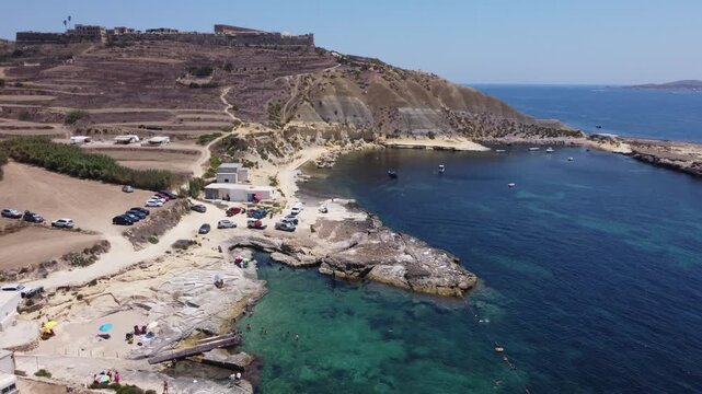 Xatt L-Ahmar, Gozo, Malta. Salt apns. serene aerial view of rocky coastline with sandy beaches and calm waters in natural setting for travel and vacation purposes. stationery perspective from above