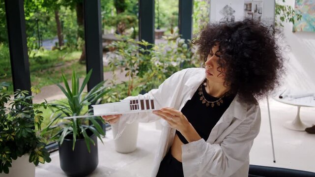 Focused African American female designer inspects building model