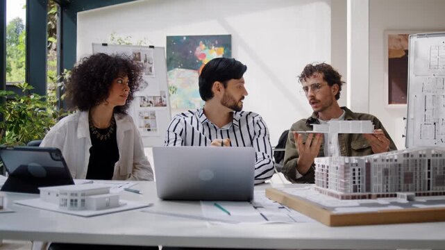 Multiethnic designers team discusses projects at laptop in office