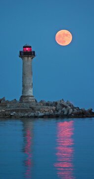 Full strawberry moon rising behind Trakata coastal lighthouse near Euxinograd beach in Varna Bulgaria