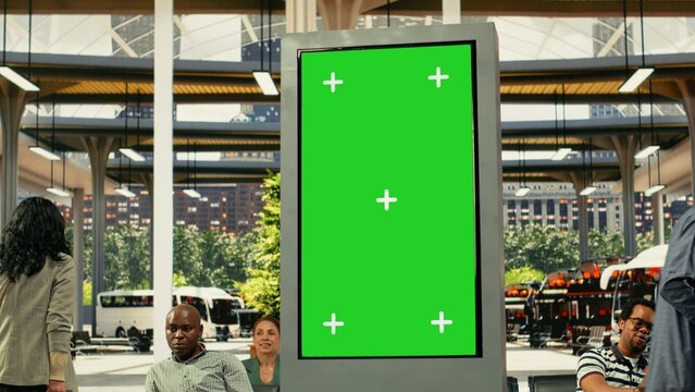 Green screen in public transportation station with passengers during weekday commute in a busy city environment.