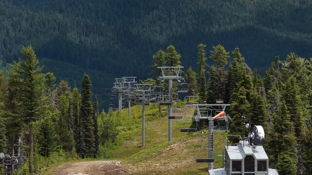 Aerial close up of chairlift infrastructure on forested mountain slope in summer in Colville National