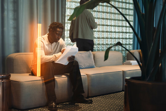 Male entrepreneur examining documents while sitting on couch in office lawn