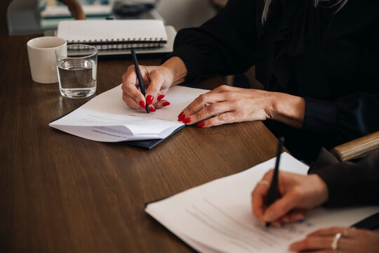 Close-up of businesswomen filling contract forms in meeting room