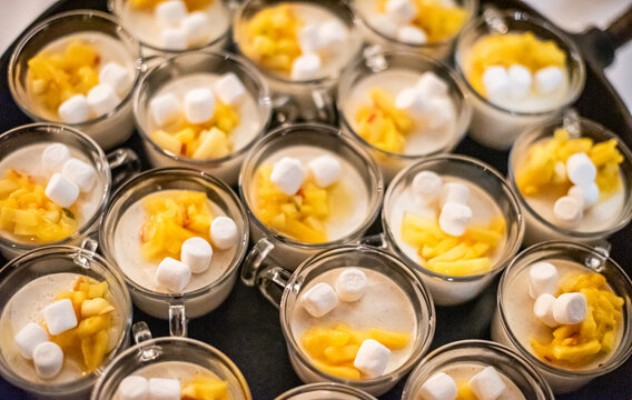 Individual dessert cups with cream fruit and marshmallows served.
