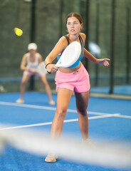 Fototapeta premium Sportive young woman and other members engaged in Padel Tennis in indoor court of tennis club