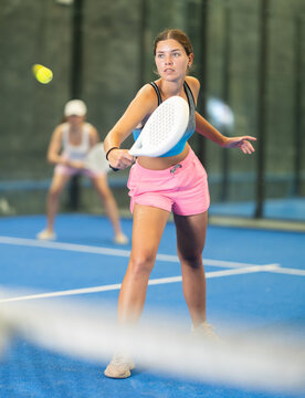 Sportive young woman and other members engaged in Padel Tennis in indoor court of tennis club