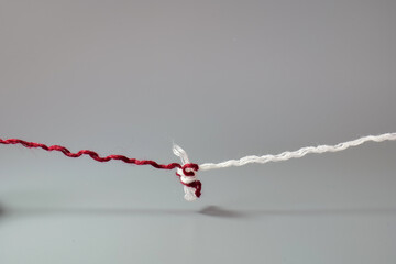 Red and white threads tied together with a knot. Minimal concept of connection, unity, relationships, trust, problem solving, and strong bonds © Hanna