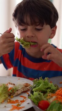 Young boy enjoying leafy salad during family meal, highlighting healthy nutrition, wholesome eating and everyday childhood wellbeing