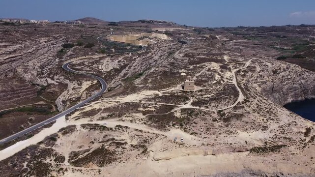Aerial view of Dwerja bay in Gozo at noon with clear skies and rock formations brown and gray earth tones and natural beauty for nature documentarie. High quality 4k footage