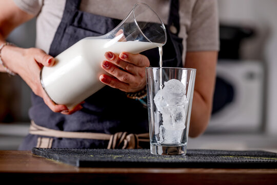 Woman Bartender Pouring Milk Into Glass With Ice
