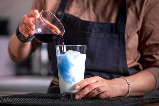 Woman Bartender Pouring Blue Matcha Tea Into Milk And Ice Glass