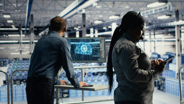 Data center technical support specialist guides customers through setting up secure company data backups. IT administrator in server facility helps users fix system errors on servers.