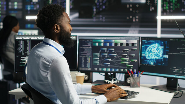 Server facility admin applying AI neural network models to set up hardware. Man works on AI programming tools in data center, optimizing system functionality.