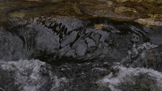 Panning shot of Mountain River flows Over Rocky Cascade.