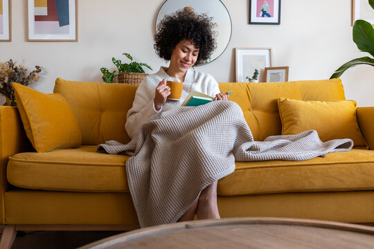 Woman relaxing at home, enjoying book and morning coffee