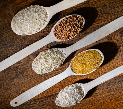 Assorted Grains and Cereals in Wooden Spoons on Rustic Wooden Background