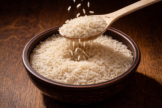 Wooden Spoon with Raw Long Grain Rice over Rustic Ceramic Bowl