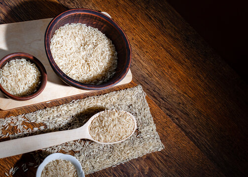 Raw Long Grain Rice in Wooden Spoon and Rustic Bowls, Flat Lay